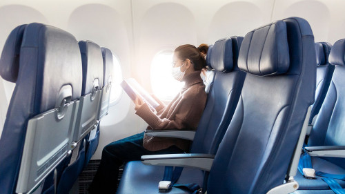 A young woman wearing face mask is traveling on airplane , New normal travel after covid-19 pandemic concept