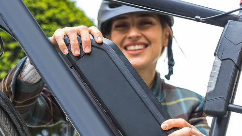 woman holding an electric bike battery mounted on frame