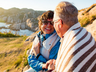Loving mature couple hiking, sitting on windy top of rock, explo