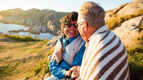 Loving mature couple hiking, sitting on windy top of rock, explo