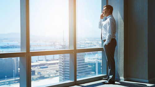 Mature business executive in top floor office space on phone