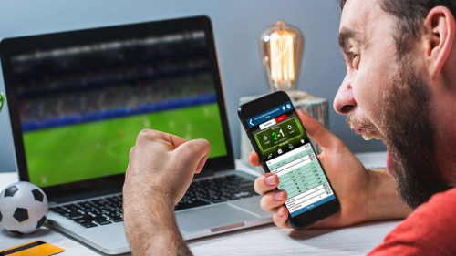 Guy being happy winning a bet in online sport gambling application on his mobile phone