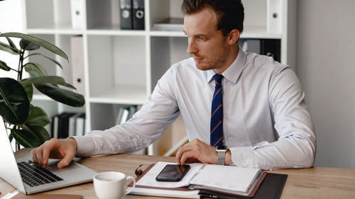 Man in shirt and tie using laptop while working