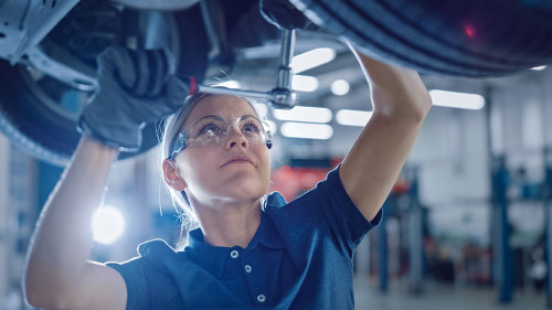 Portrait Shot of a Female Mechanic Working Under Vehicle in a Ca