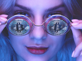Portrait of a beautiful young blond woman with red lips in glasses with bitcoins close-up. Cryptocurrency concept. Creative neon lighting