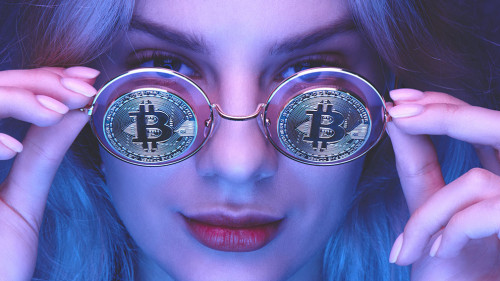 Portrait of a beautiful young blond woman with red lips in glasses with bitcoins close-up. Cryptocurrency concept. Creative neon lighting