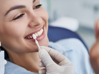 Male dentist choosing color for woman teeth