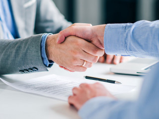 Businessmen handshaking over signed contract.