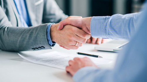 Businessmen handshaking over signed contract.