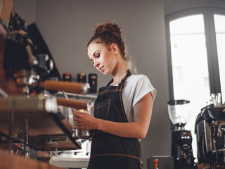 Portrait of professional barista woman in apron making coffee us