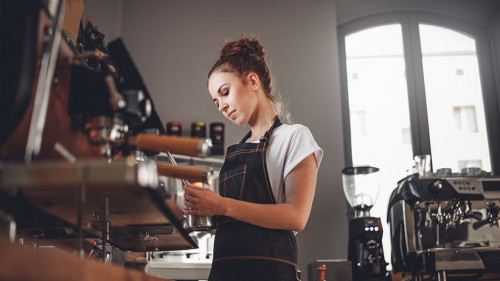 Portrait of professional barista woman in apron making coffee us