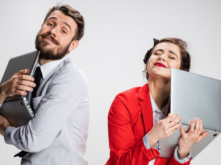 The young businessman and businesswoman with laptops on gray background