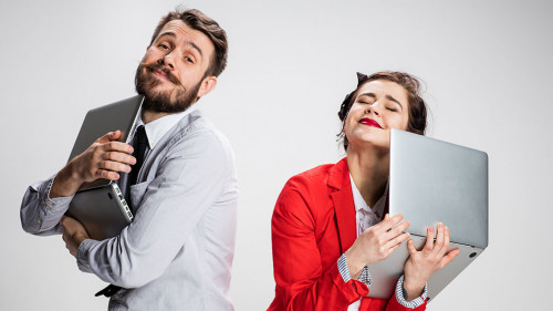 The young businessman and businesswoman with laptops on gray background