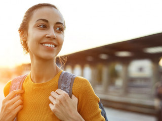 portrait of a young woman traveler with small backpack on the railway stantion