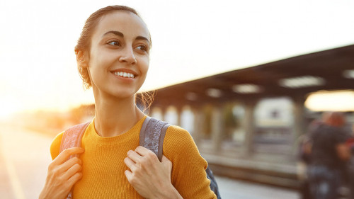 portrait of a young woman traveler with small backpack on the railway stantion