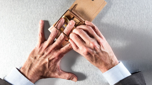 businessman removing his hand a mouse trap with bank note