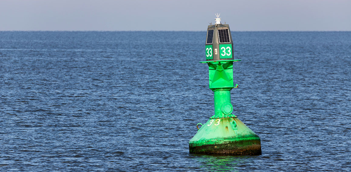green lateral buoy at the edge of a fairway