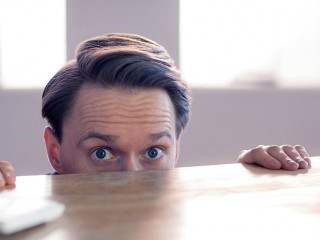 Nervous businessman peeking over desk