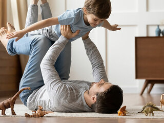 Young father playing at home with preschooler son