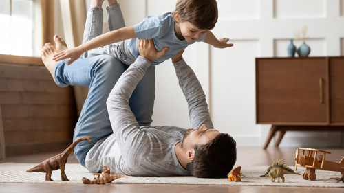 Young father playing at home with preschooler son