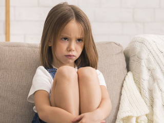 Concerned Little Girl Sitting Alone At Therapy Session With Children Psychologist