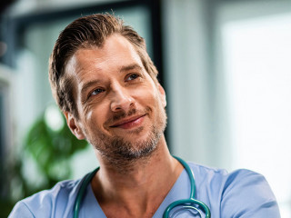 Smiling male doctor talking to his patient while going through medical reports at his office.