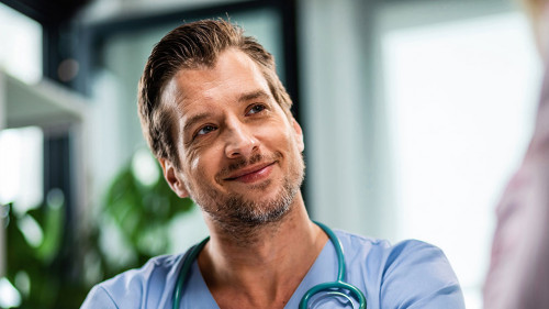 Smiling male doctor talking to his patient while going through medical reports at his office.