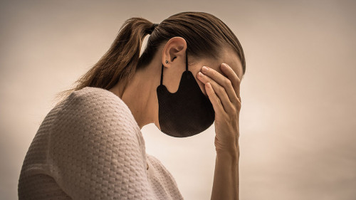 Stressed female wearing protective face mask. Coronavirus, fear,