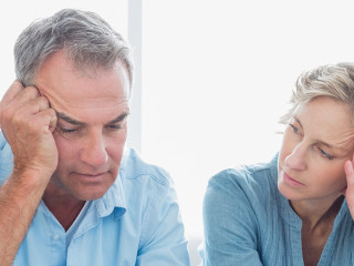 Worried couple using their laptop to pay their bills at home in the living room