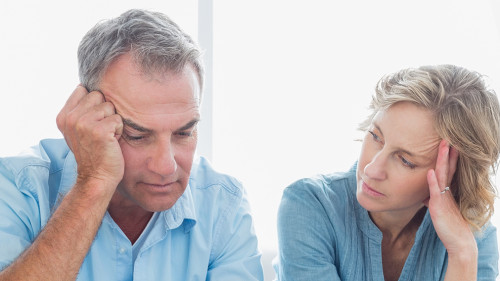 Worried couple using their laptop to pay their bills at home in the living room