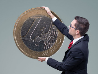 Geldanlage – Mann im Anzug stapelt Geldmünzen