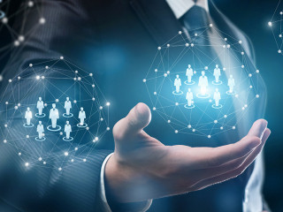 A businessman holding a system of digital spheres with human figures models.