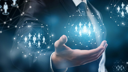 A businessman holding a system of digital spheres with human figures models.