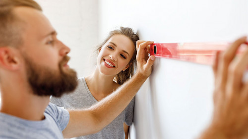 young happy couple is repairing and painting wall at home