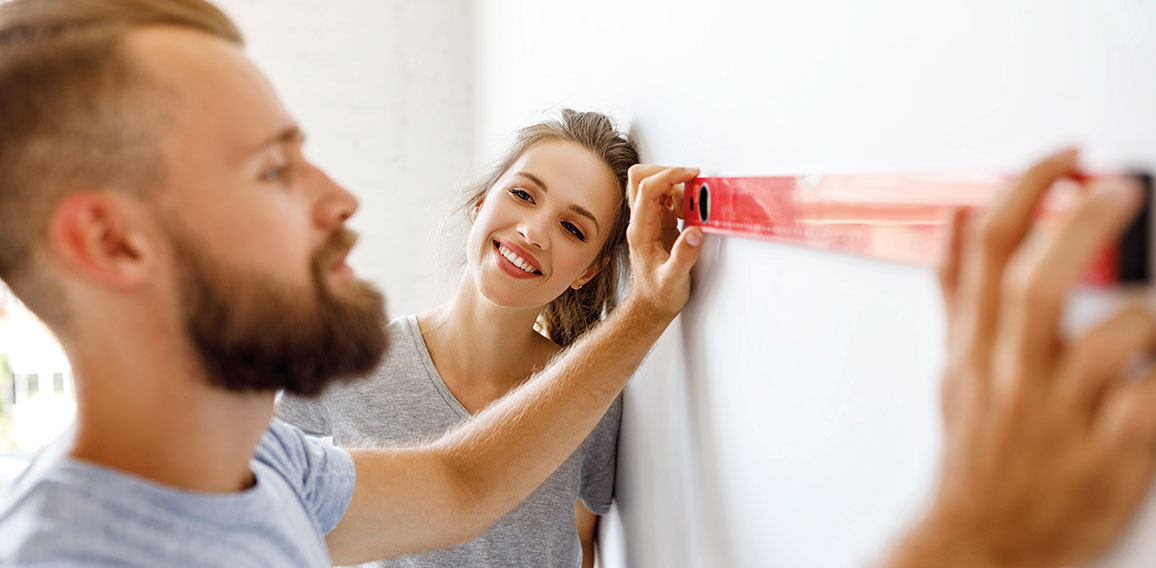 young happy couple is repairing and painting   wall at home