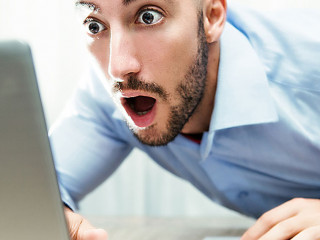 uomo stupito davanti al monitor del notebook