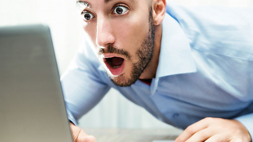 uomo stupito davanti al monitor del notebook