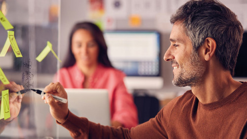 Brainstorming Creative Business Team Putting Ideas Onto Glass Screen In Office
