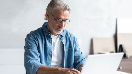 Middle-aged man working from home-office on laptop.