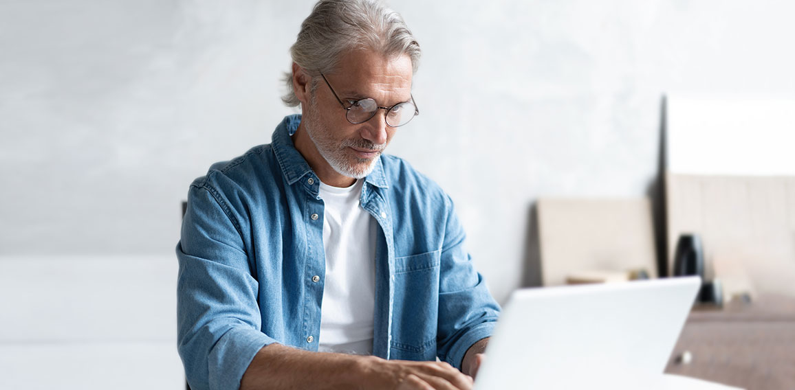 Middle-aged man working from home-office on laptop.