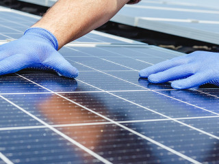 Male worker hands in glows on solar panel, technician installing solar panels on roof. Alternative energy sun energy power, ecological concept. Long web banner