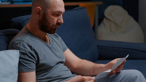 Angry stressed depressed man reading bad news in mail letter