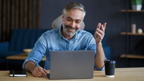 Portrait of grey-haired senior handsome smiling man working from home. Communication online with colleagues and video conference. Online meeting, video call, remote working