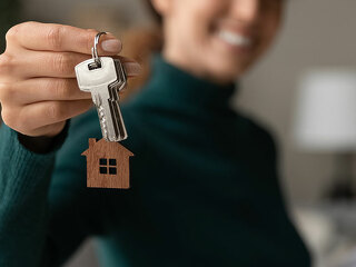 Close up focus on keys, smiling woman realtor selling apartment