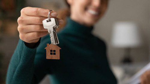 Close up focus on keys, smiling woman realtor selling apartment