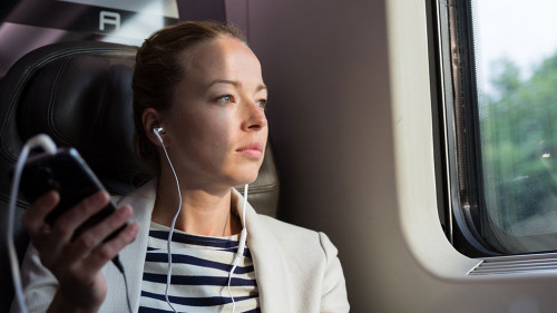 Businesswoman communicating on mobile phone while traveling by train.