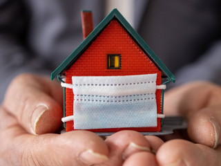 Senior businessman holding model house wearing protective medica