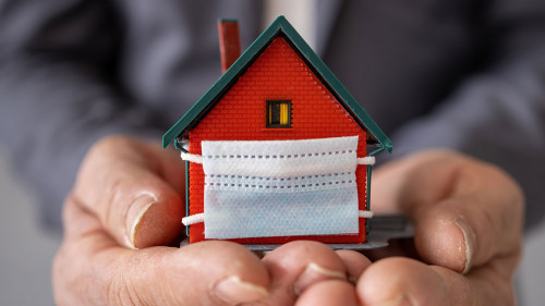 Senior businessman holding model house wearing protective medica