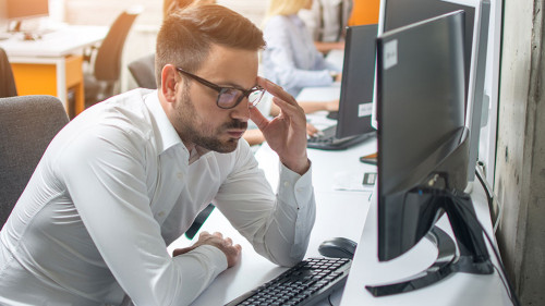 Worried businessman looking at computer screen at his workplace