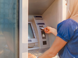 Young woman withdrawing money from credit card at ATM machine